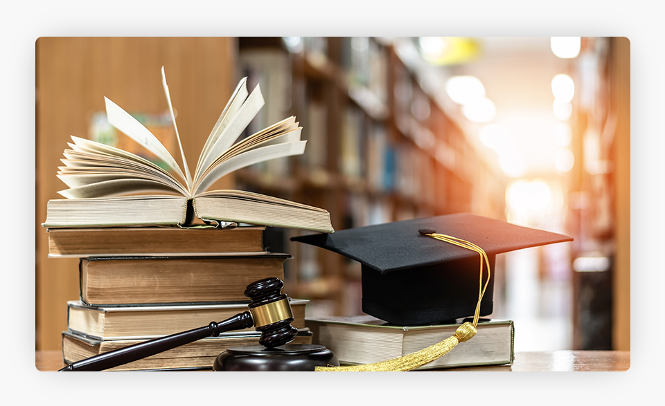 Un mazo junto a unos libros y un birrete de graduación.